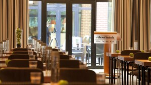 A restaurant area with tables and chairs, a sign for 'relexa hotels Die feine Art', and a view of the outside.