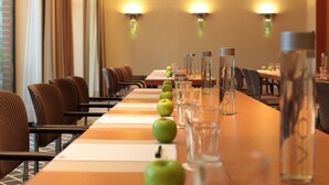 A conference room with a long table, chairs, and a row of green apples.
