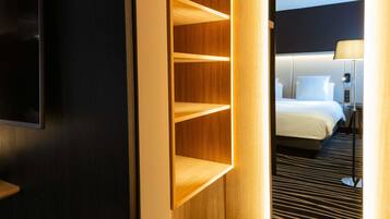 Una habitación de hotel con una cama, un televisor montado en la pared y un estante de madera.