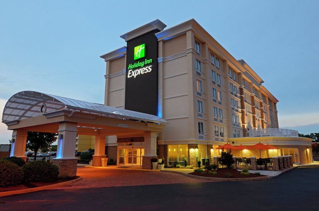 A Holiday Inn Express hotel with a prominent sign, a covered entrance, and outdoor seating area.
