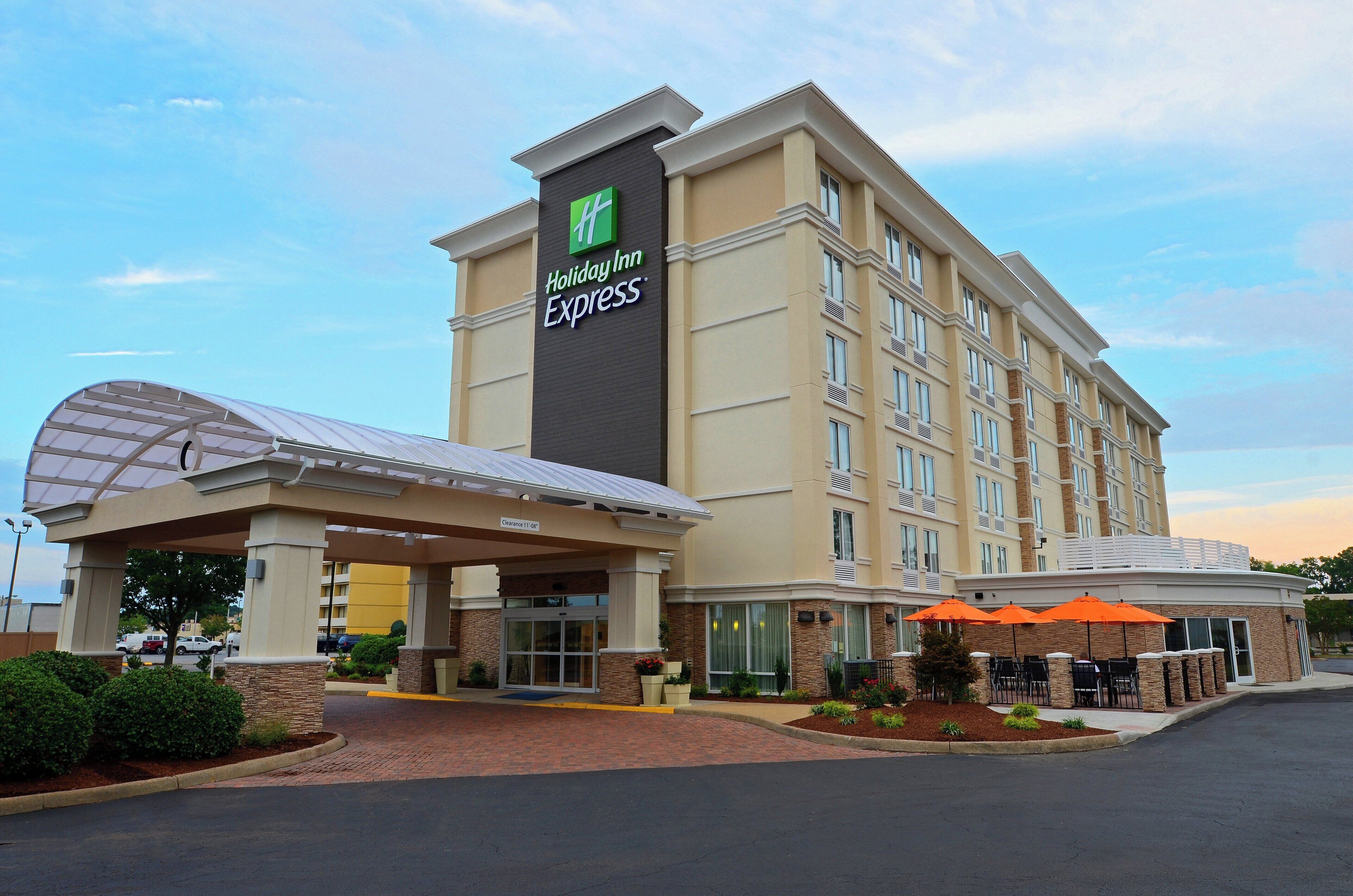 Un hotel Holiday Inn Express con ingresso coperto, area salotto esterna e cielo sereno.