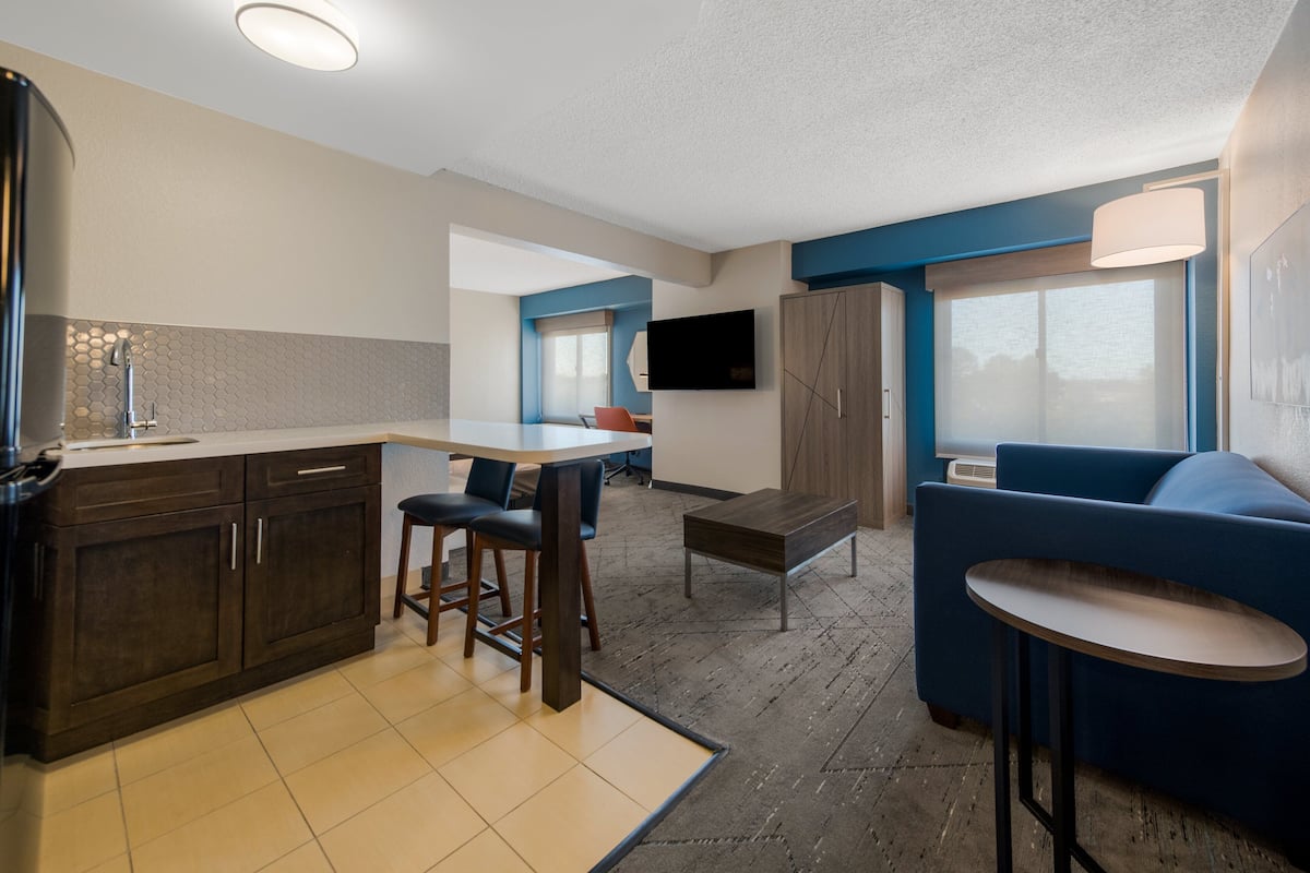 Cozy living space with a kitchenette, bar area, and seating area featuring a sofa and flat-screen TV.