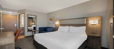 Ein Hotelzimmer mit einem großen Bett, einem Schreibtisch, einem Sessel, einer Couch und einem Badezimmer.