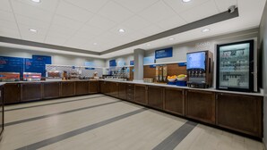 A spacious, modern kitchen area with wooden cabinets, a central island, and various breakfast items displayed on the counters. - Holiday Inn Express Hampton - Coliseum Central by IHG (Hampton)