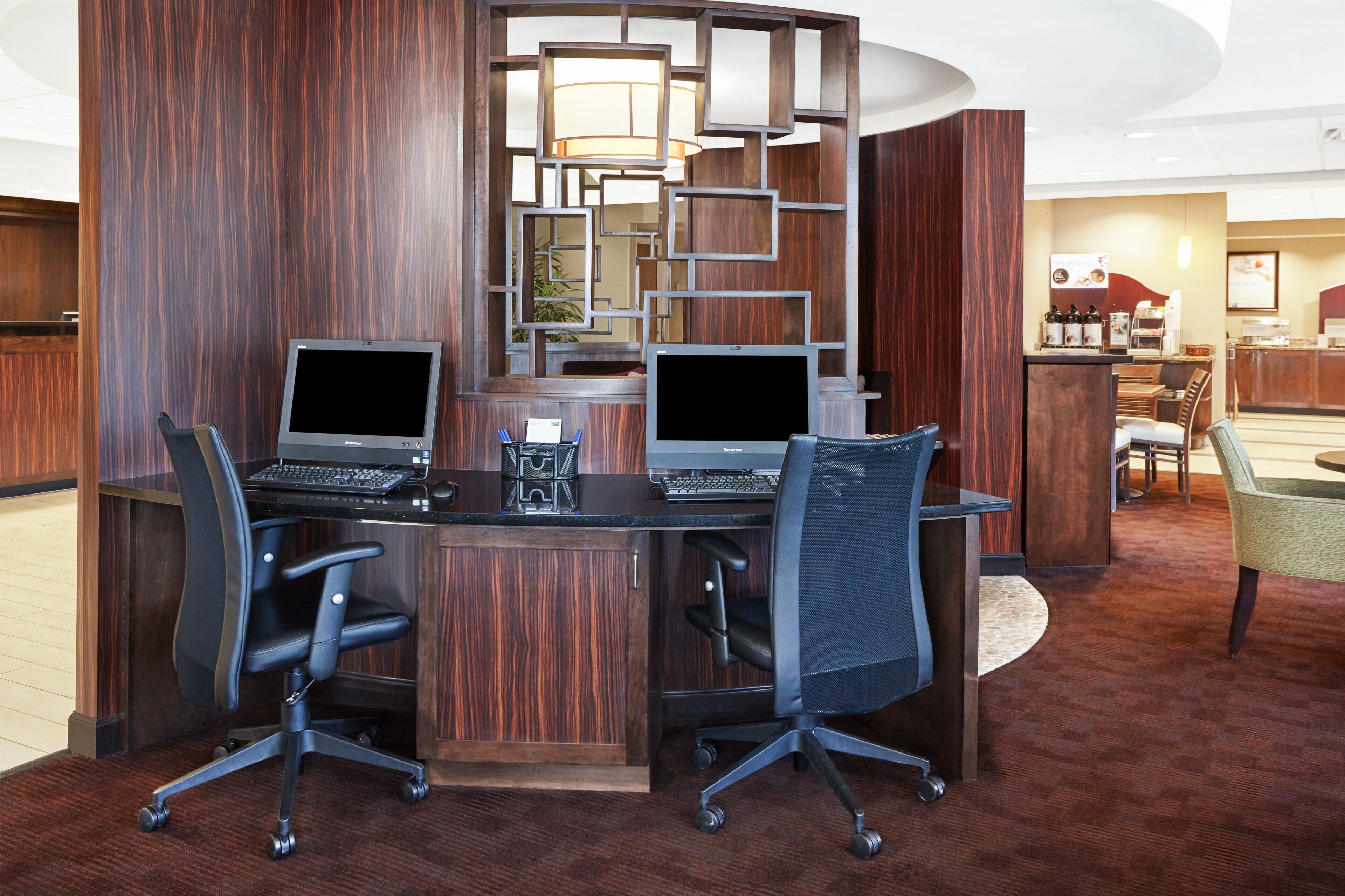 A conference room with two desks, each with a laptop and a chair.