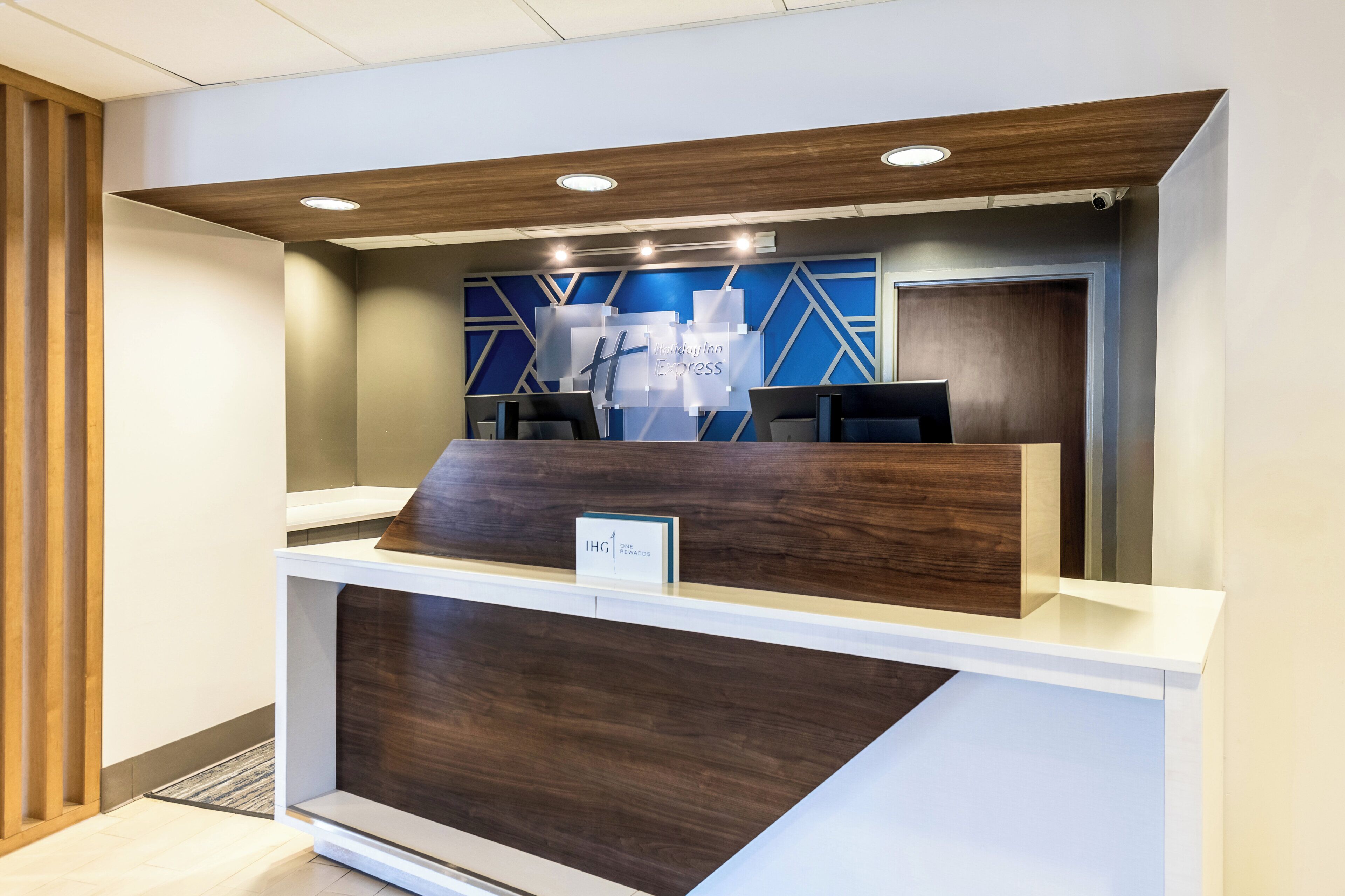 A reception desk with a modern design, featuring a wooden front panel and a blue geometric wall pattern in the background.