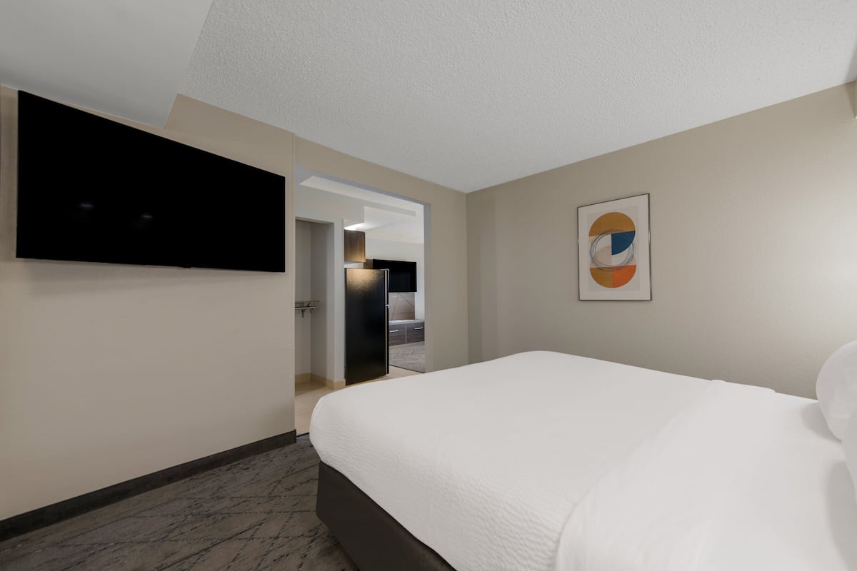 Relax in a stylish room with a large bed, flat-screen TV, and modern artwork.