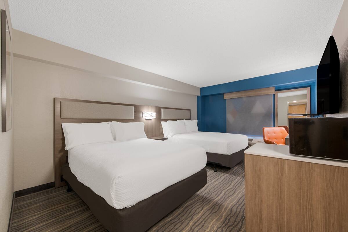 Hotellihuone, jossa on kaksi sänkyä, työpöytä, televisio ja ikkuna.