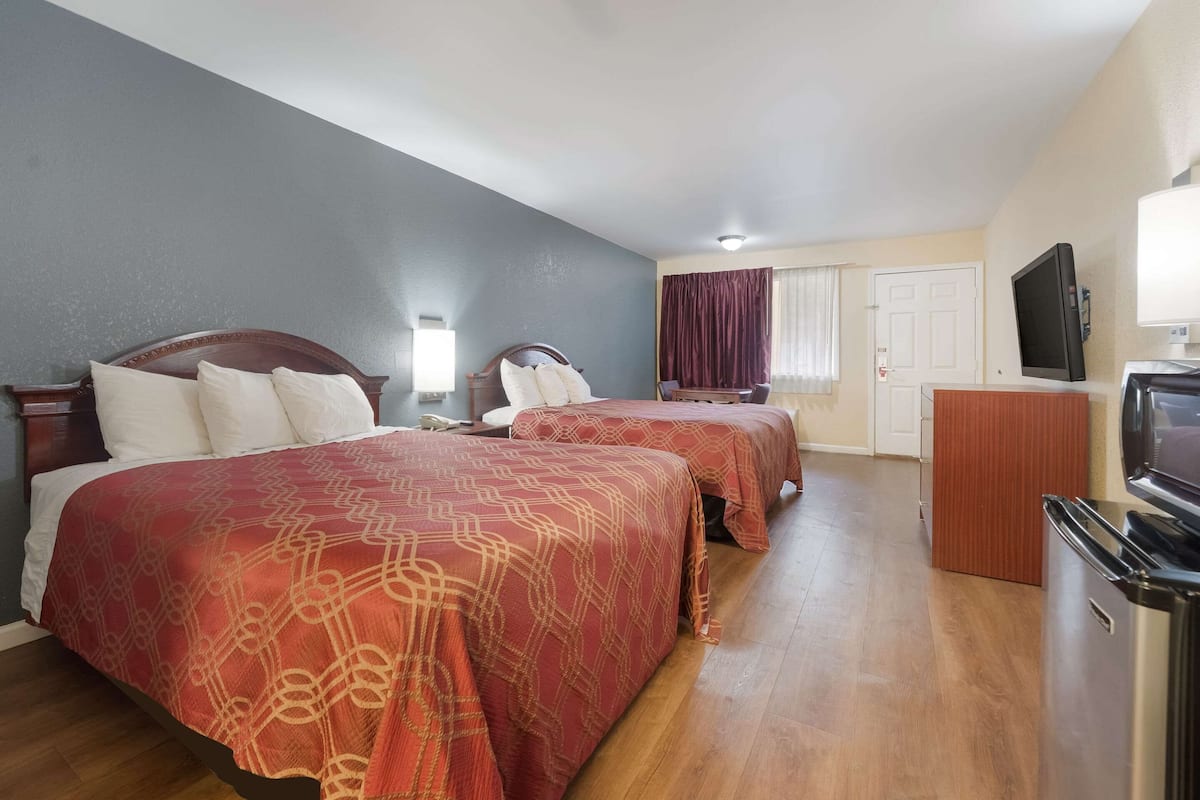 A hotel room with two beds, a TV, a desk, and a wardrobe.