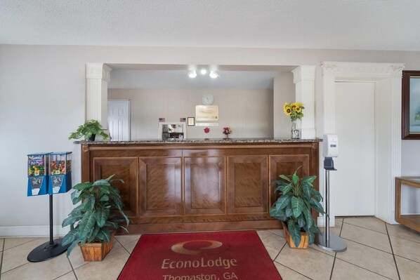 A reception desk with a clock, framed certificates, and a welcome sign. - Econo Lodge Thomaston (Thomaston)