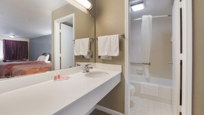 Un baño de hotel con un espejo grande, un lavamanos, una bañera y una ducha.