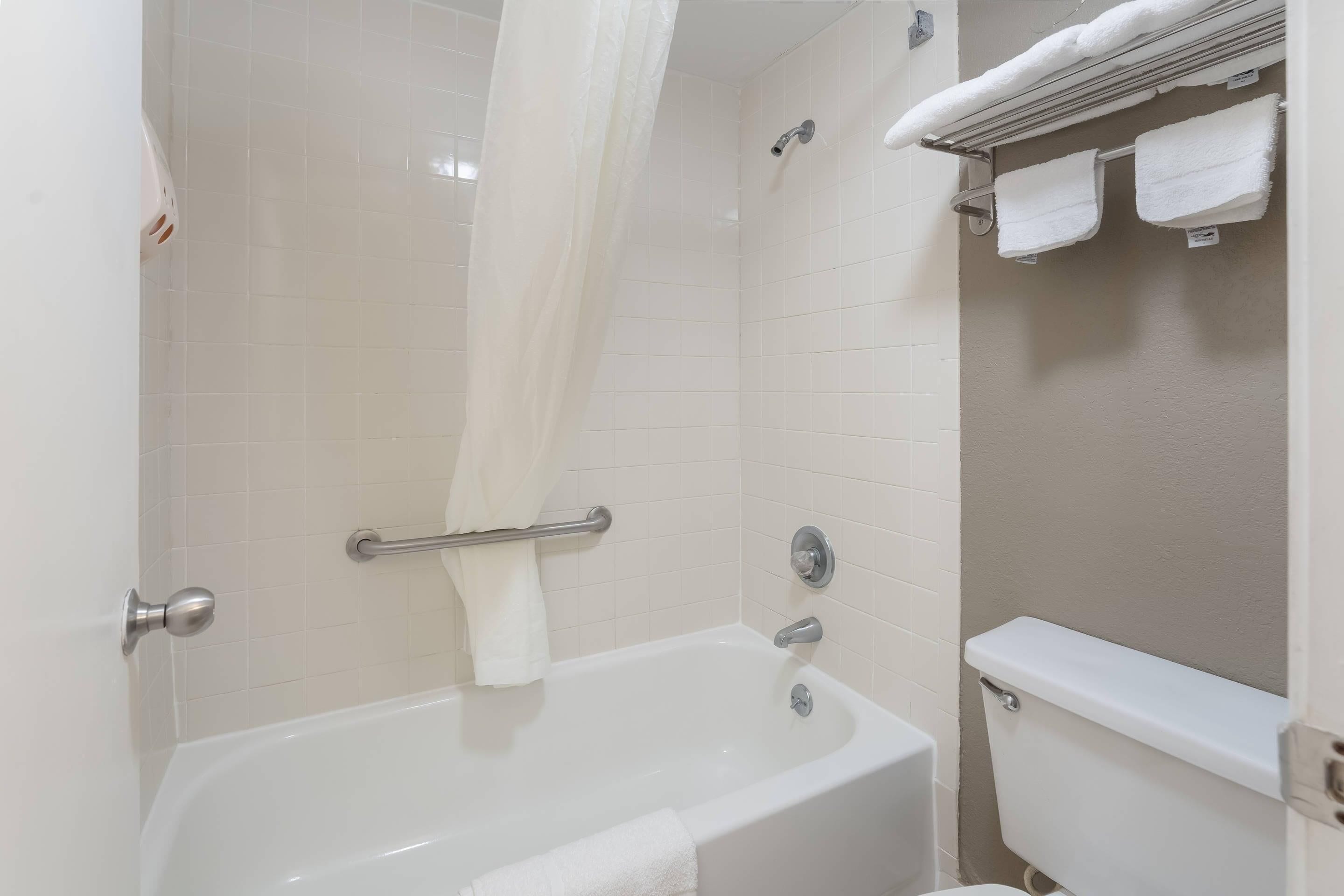 A bathroom with a bathtub, a shower curtain, a towel rack, and a toilet.