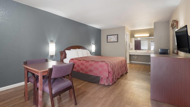 Una habitación de hotel con una cama, un escritorio con una silla, un televisor y un baño a la vista.