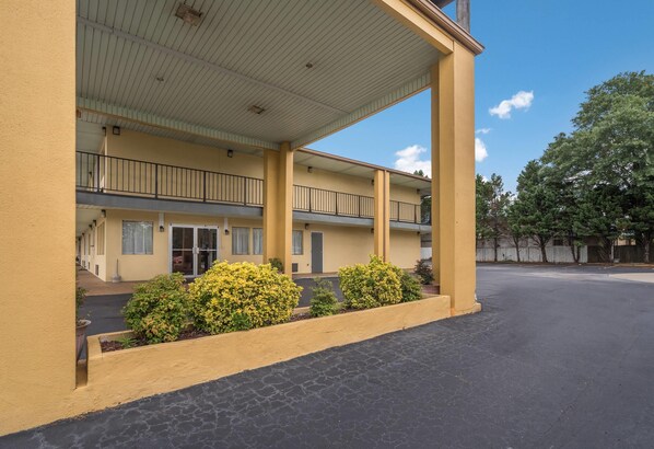 A two-story motel with a covered parking area, a central courtyard with plants, and a clear blue sky. - Econo Lodge Thomaston (Thomaston)