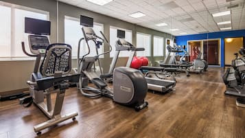 Un gimnasio con equipo de ejercicio variado, incluyendo cintas de correr, elípticas y máquinas de pesas.
