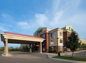 A hotel with a covered parking area, multiple floors, and a clear sky. - Holiday Inn Express & Suites Detroit - Farmington Hills by IHG (Northville)