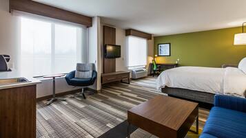 A hotel room with a bed, a desk, a chair, a TV, and a window.