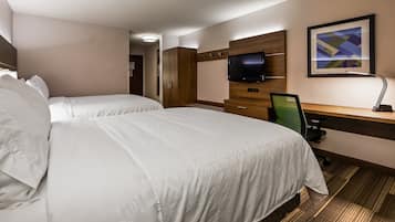 A hotel room with two beds, a desk, a chair, a television, and a framed picture on the wall.