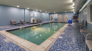 A swimming pool with a tiled floor, poolside chairs, and a lifeguard chair. - Holiday Inn Express & Suites Detroit - Farmington Hills by IHG (Northville)