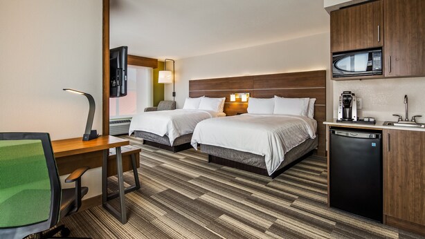 Une chambre d’hôtel avec deux lits, un bureau, une chaise, un four à micro-ondes, une machine à café et un lave-vaisselle.