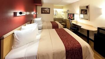 A hotel room with two beds, a desk, a chair, a television, and a mirror.