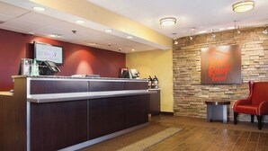 Un comptoir d’accueil doté d’un écran numérique, d’une machine à café et d’une enseigne indiquant « Red Roof Inn ».