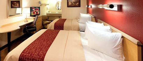A hotel room with two beds, a desk, a television, and a bathroom.