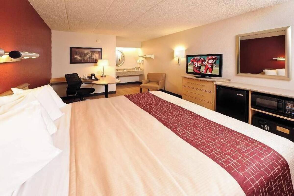 Une chambre d’hôtel avec un grand lit, un bureau avec une chaise, une télévision et un miroir.