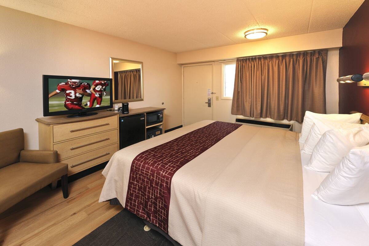 Une chambre d’hôtel avec un lit, une télévision, un bureau et une chaise.