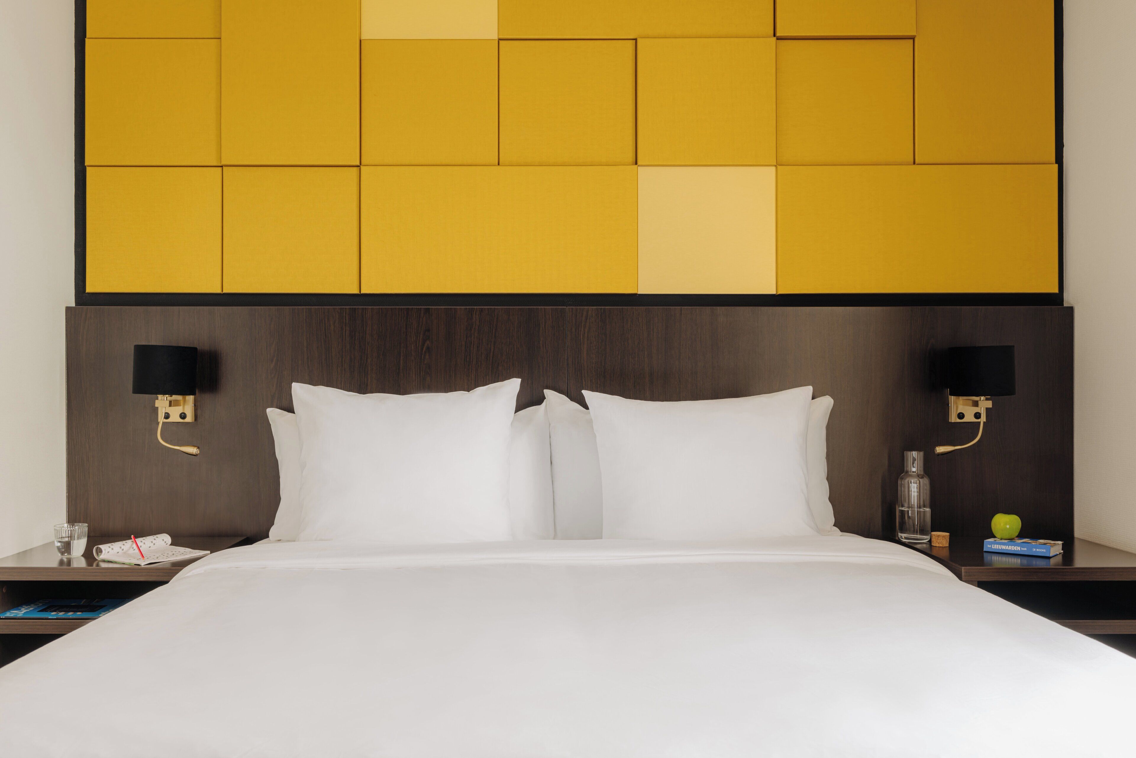 Habitación de hotel con una cama grande, dos mesitas de noche y un cabecero con estampado geométrico.