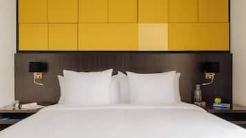 Habitación de hotel con una cama grande, dos mesitas de noche y un cabecero con estampado geométrico.