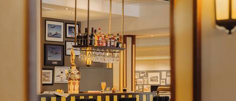 A bar area with a counter, chairs, and a hanging light fixture.