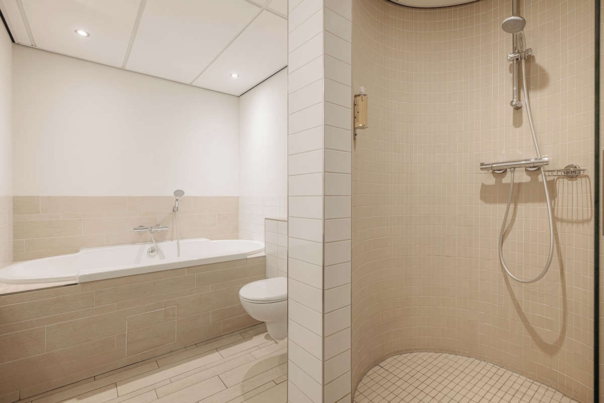 Ein modernes Badezimmer mit Badewanne, Toilette und Duschbereich.