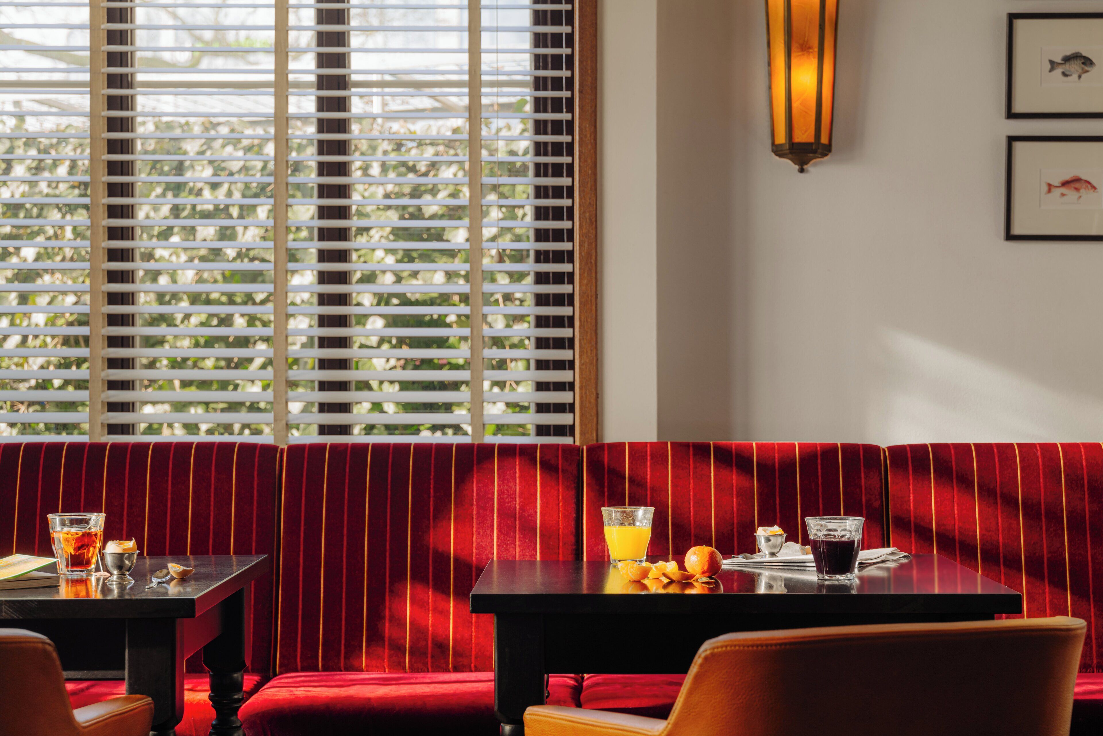 A dining area with a table and bench, a window with blinds, and a wall-mounted light fixture.