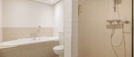 Un baño moderno con bañera, inodoro y zona de ducha.