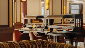 A hotel lobby with a reception desk, seating area, and a large window with curtains.