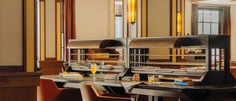 Un hall de hotel con mostrador de recepción, zona de estar y un gran ventanal con cortinas.