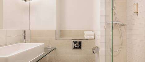 A modern bathroom with a glass-enclosed shower, a white bathtub, and a toilet.