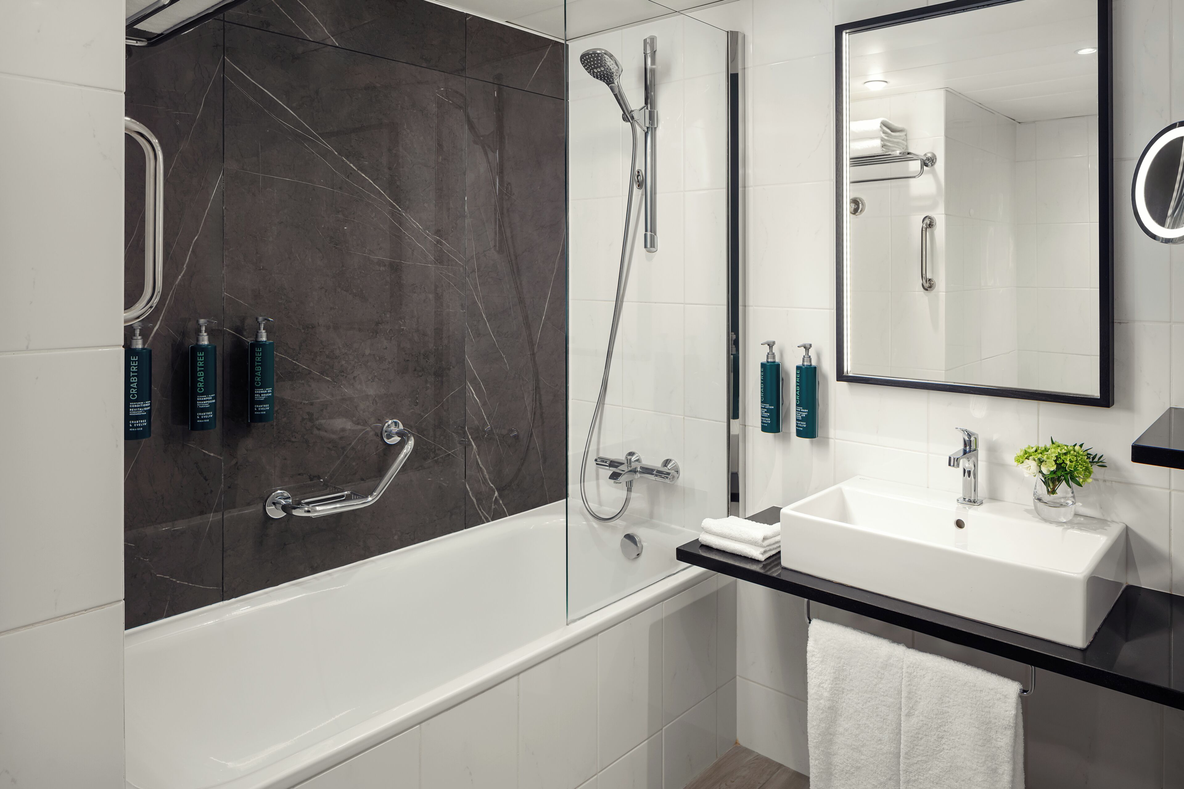 Une salle de bain moderne avec une douche à parois de verre, un lavabo blanc et un miroir.