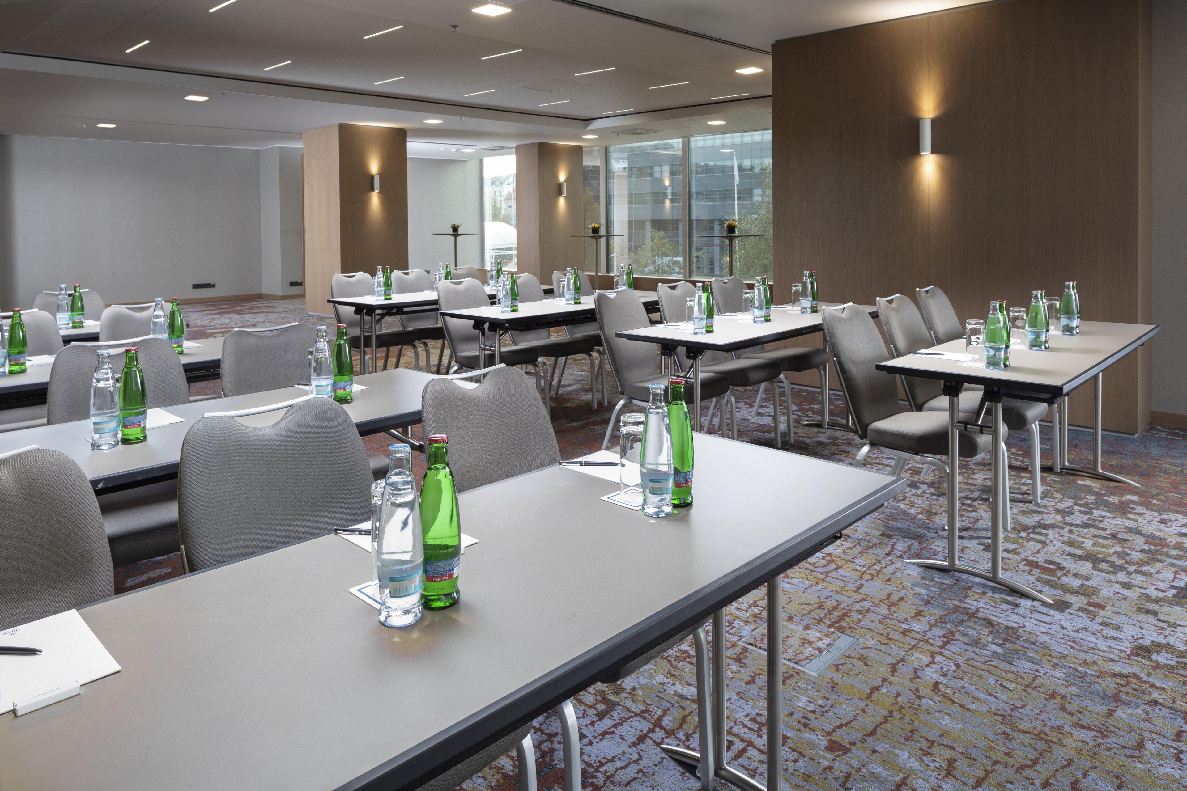 Un salón de conferencias con mesas, sillas y botellas de agua.