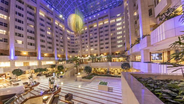 Un hall d’hôtel à plusieurs niveaux, doté d’un atrium central, de nombreux étages et de divers espaces aménagés pour s’asseoir.