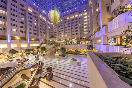 A multi-level hotel lobby with a central atrium, multiple floors, and a variety of seating areas.