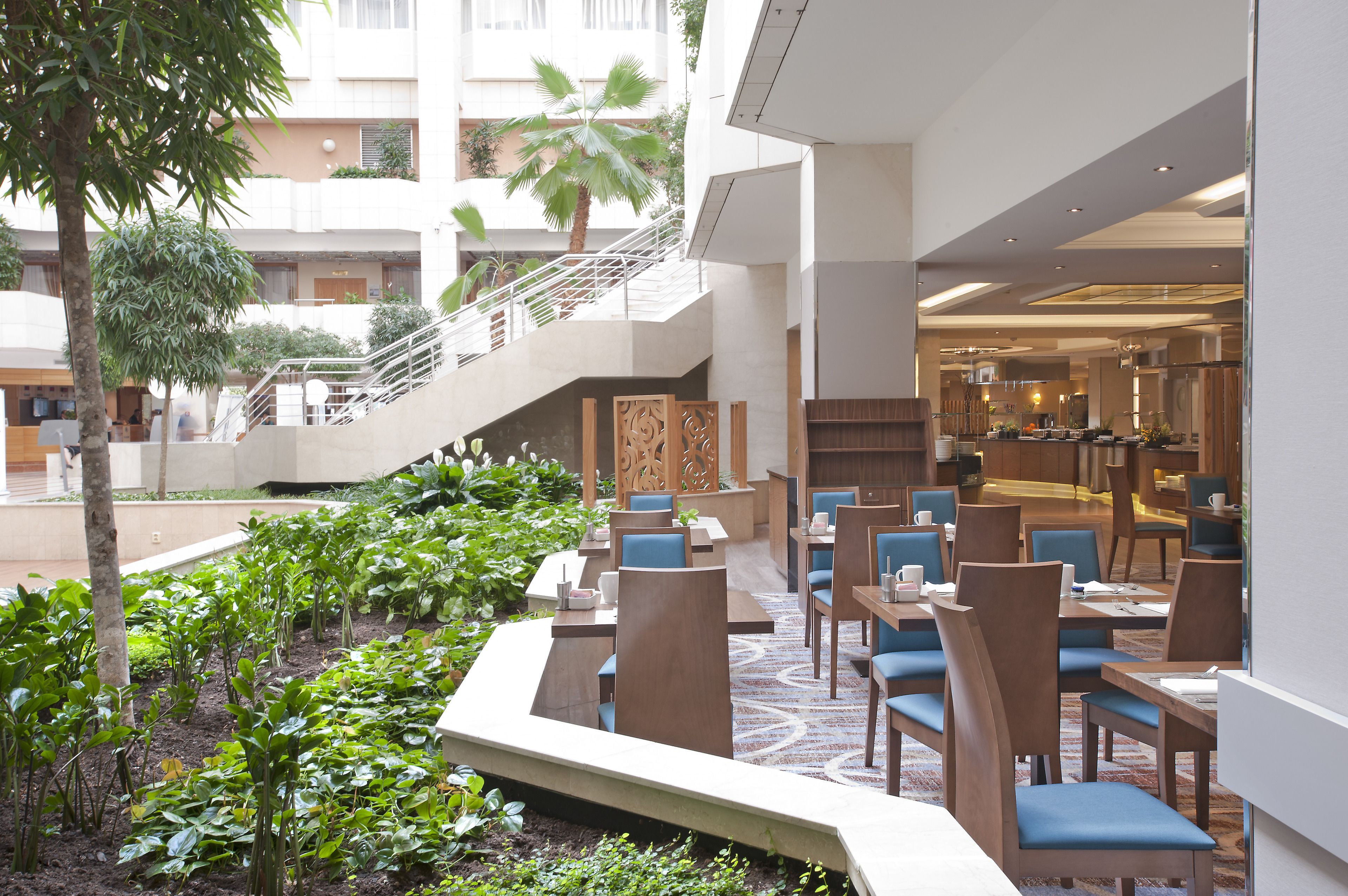 Un vestíbulo de hotel con zona de comedor, una escalera y vistas del exterior del edificio.