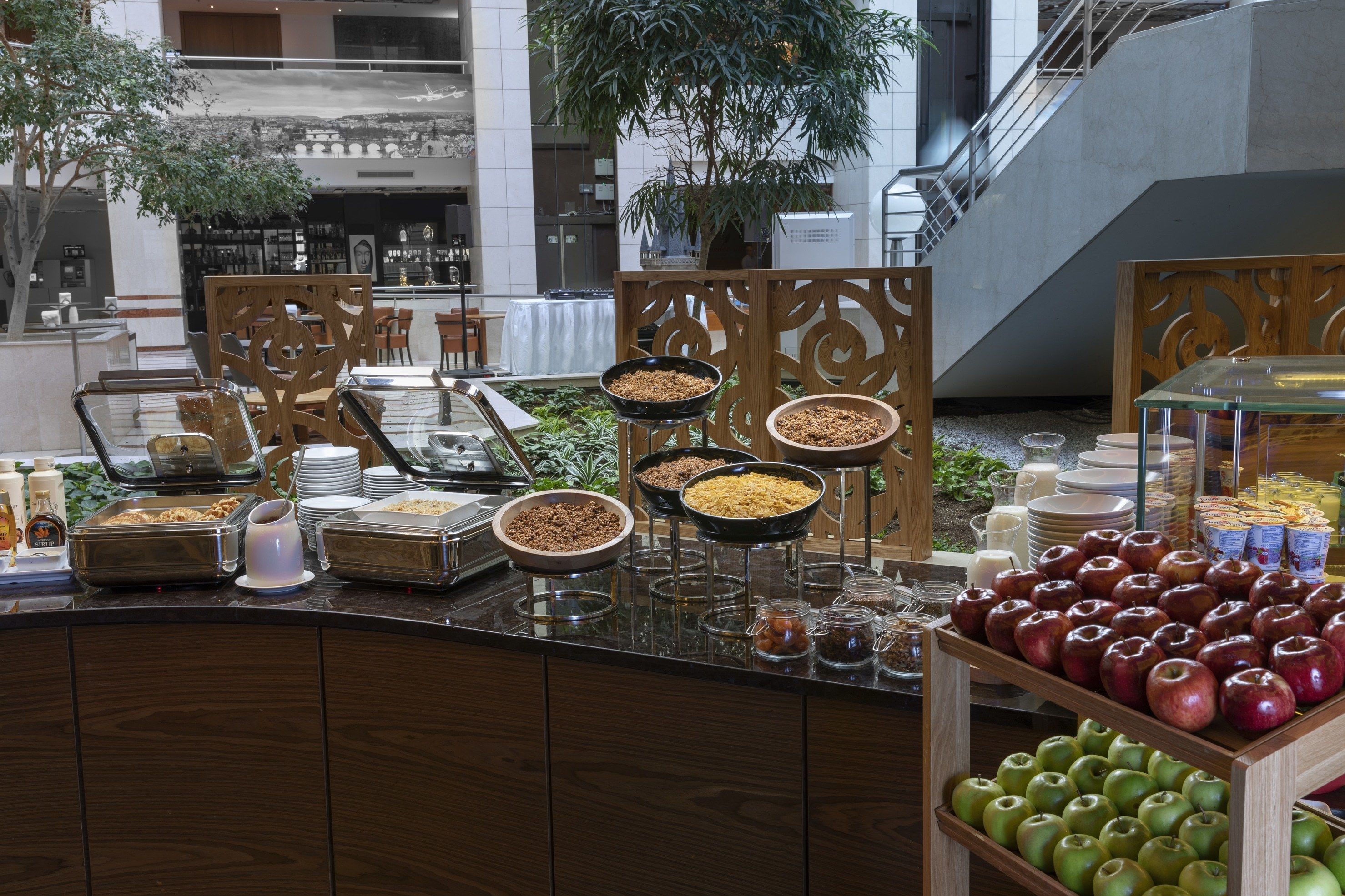 Espaço de buffet com diversos alimentos e uma exposição de maçãs.