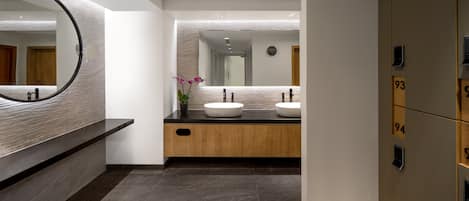Un baño moderno con un espejo grande, dos lavamanos, una orquídea en maceta y un armario de madera.