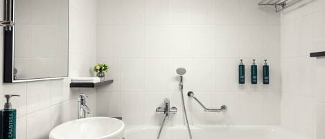 A modern bathroom with a white sink, a bathtub, and a shower. There are toiletries on the wall and a towel rack.