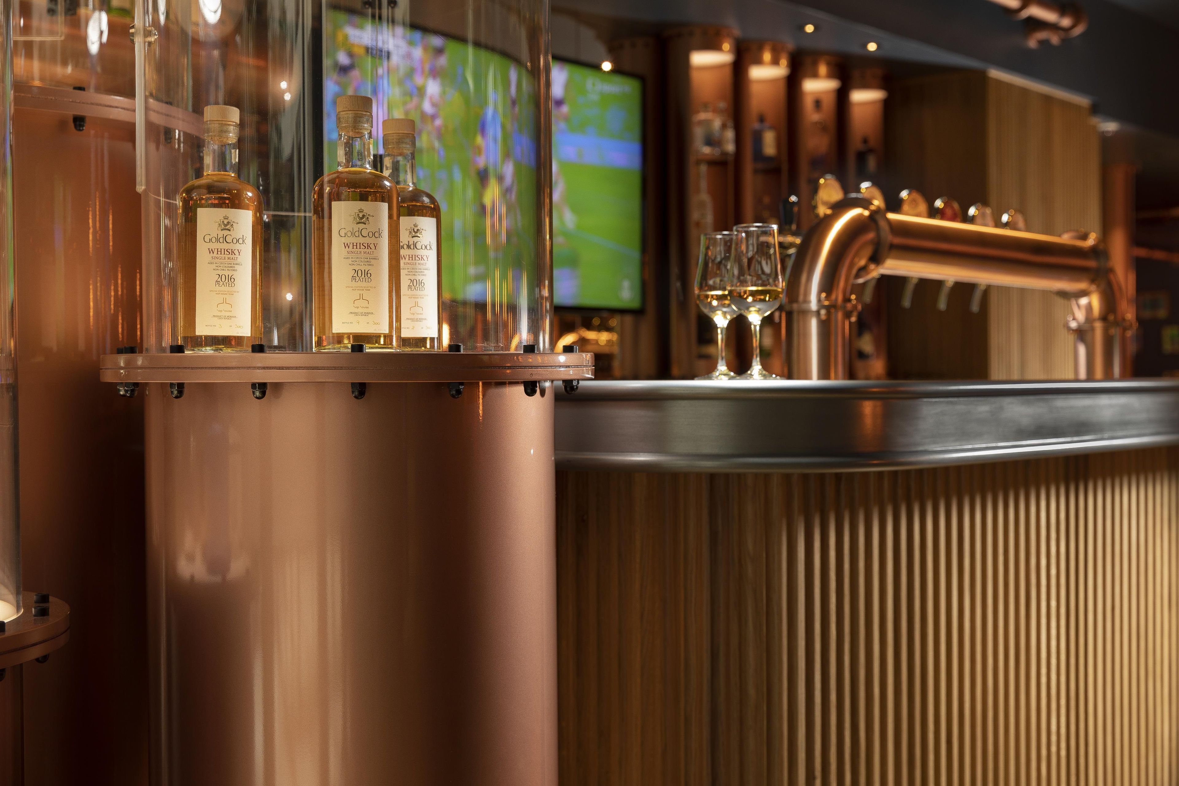 A bar area with copper fixtures and bottles of GoldCock whisky.