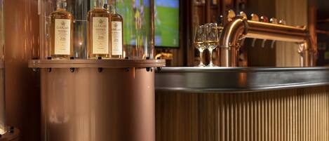 A bar area with copper fixtures and bottles of GoldCock whisky.