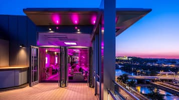 Ein moderner Hotelbalkon mit Glastür, Blick auf die Stadtlandschaft und Holzboden.