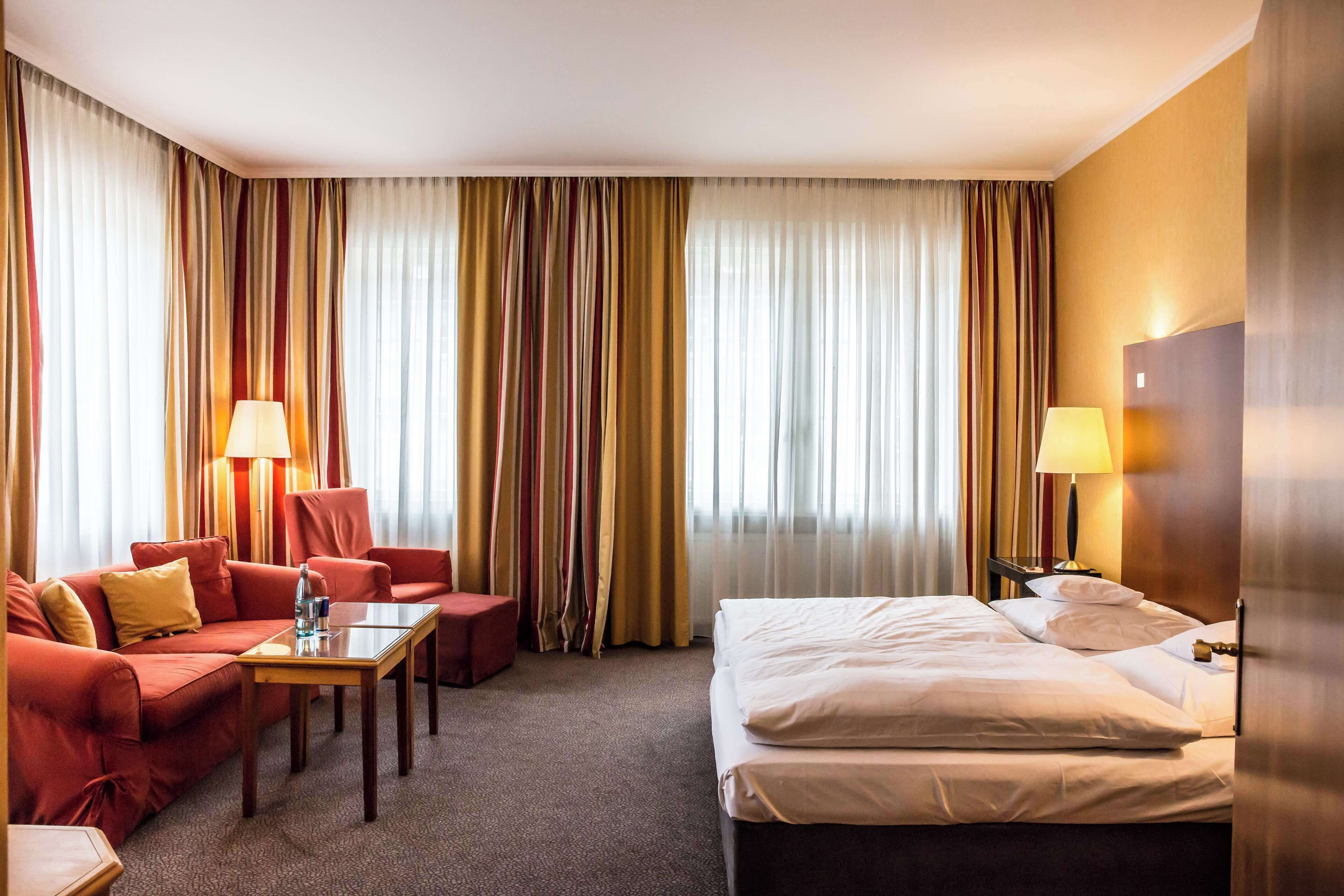 Una habitación de hotel con una cama, un sofá, una mesa y dos lámparas.